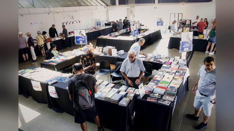 Visitors browsing tables of Persian books at the book fair, Tirgan 2023