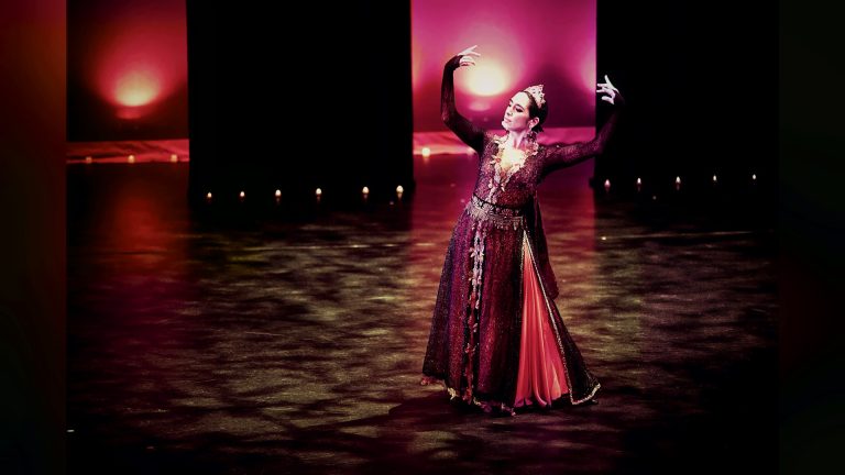 Dancer in a traditional dress performing on a red-lit stage, Tirgan 2013