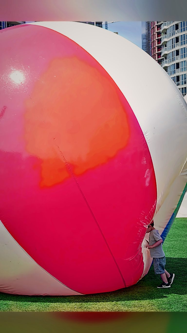 Child pushing a giant inflatable ball on the lawn, Tirgan 2013